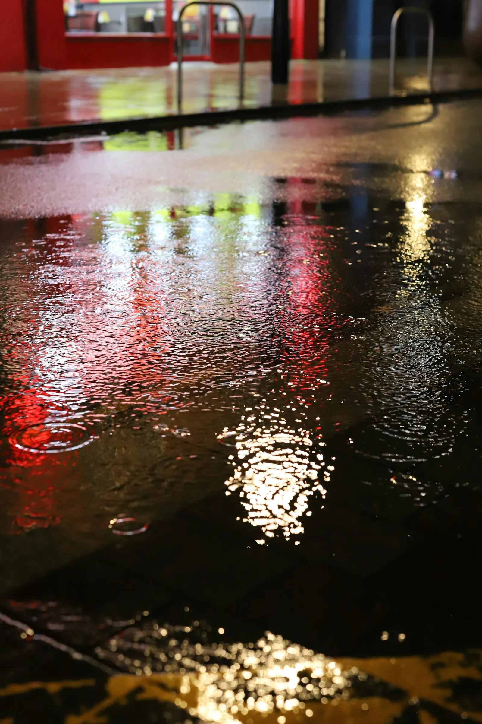 Colorful reflections across an empty rainy street at night