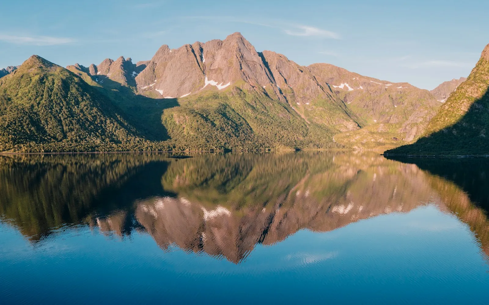 Jagged mountains reflected in still water at dawn