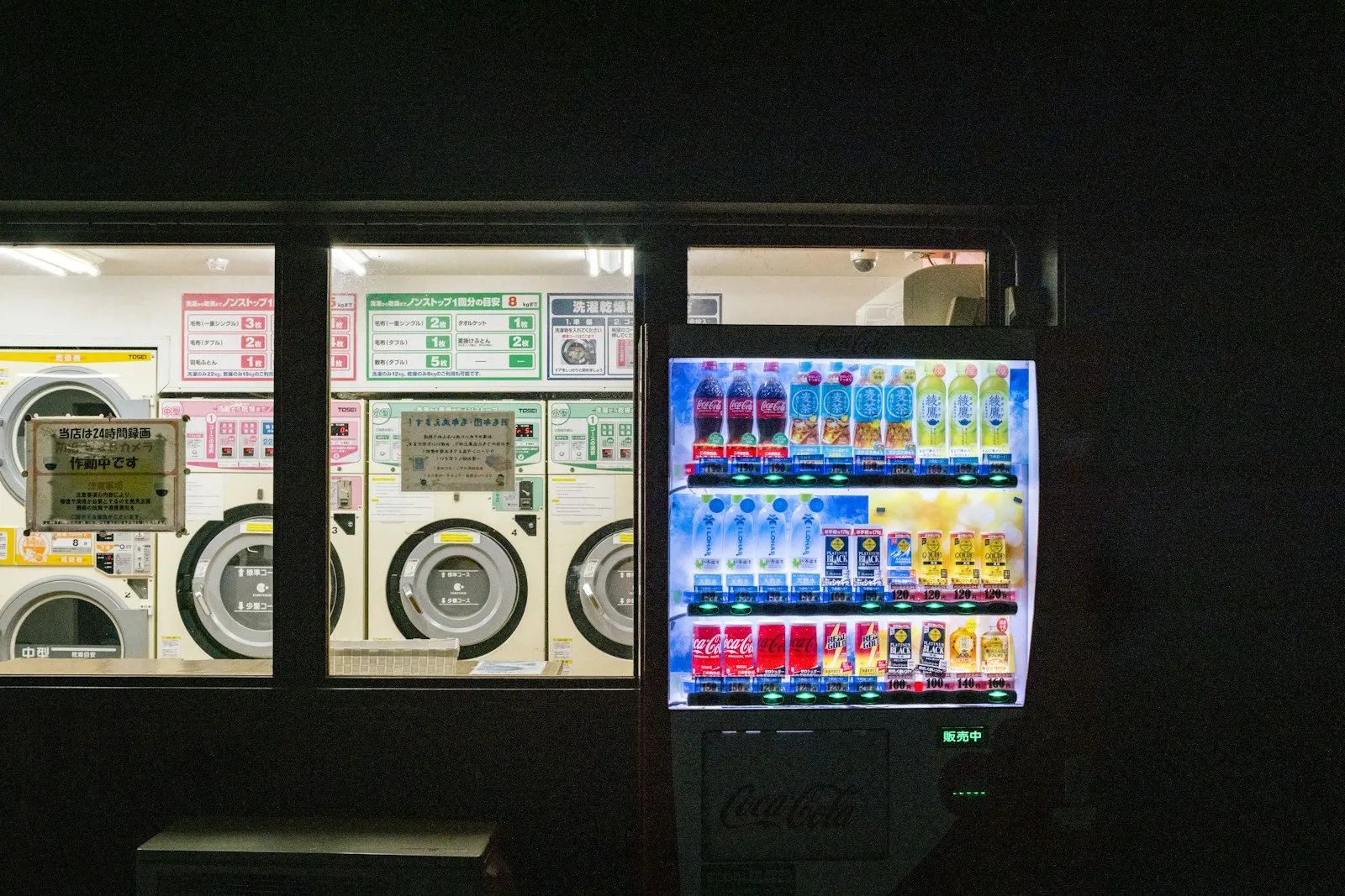 A vending machine and laundry machines glowing at night